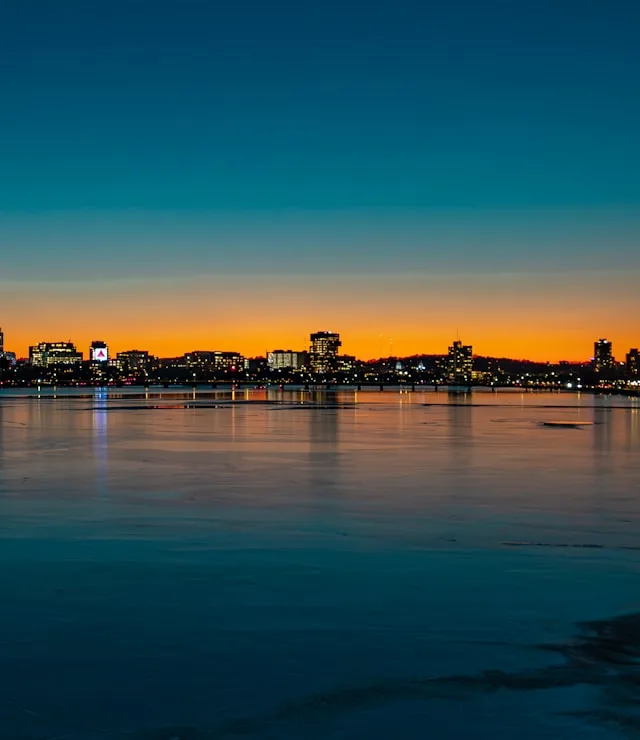 Beleuchtete Skyline von Boston am Wasser in der Abenddämmerung